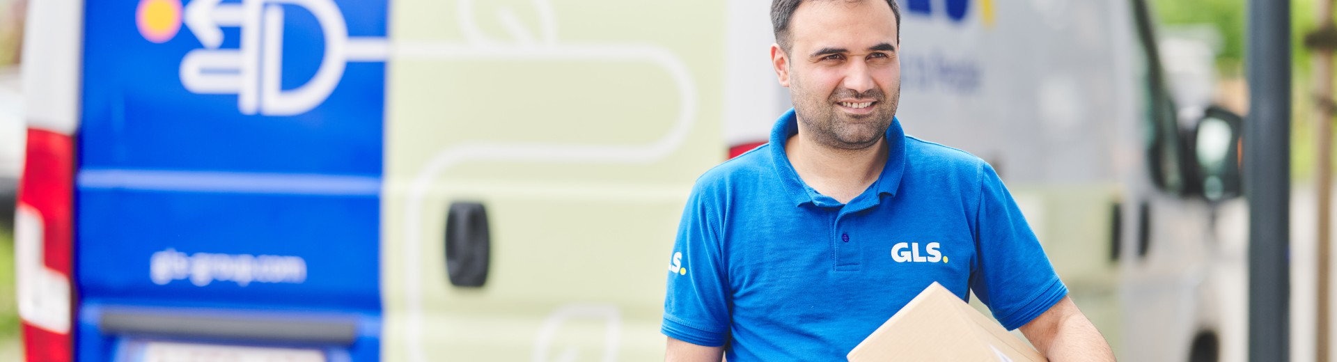 Chauffeur qui tient un colis devant sa camionnette électrique