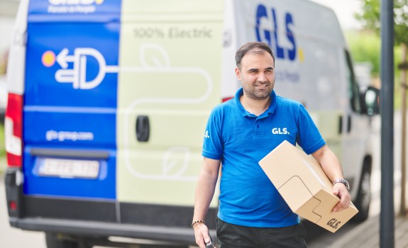 Chauffeur qui tient un colis devant sa camionnette électrique